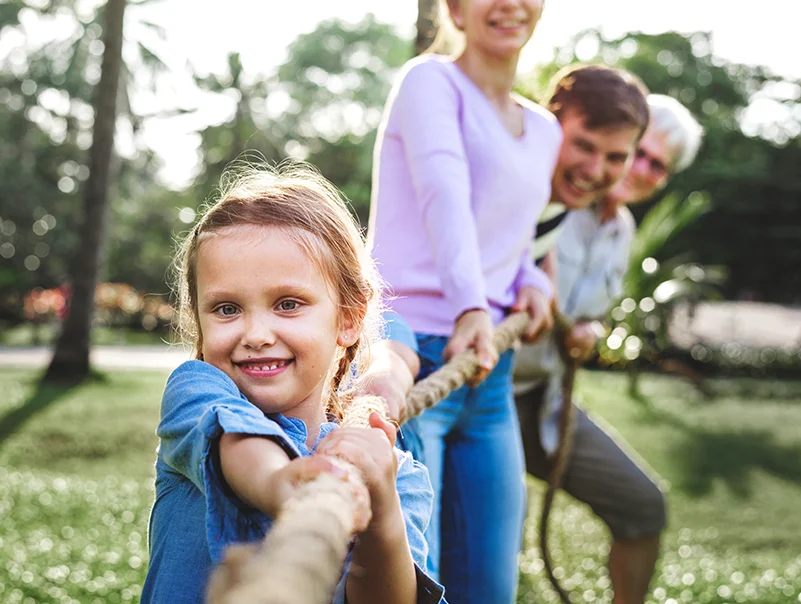 Familie zieht gemeinsam an einem Seil im Freien