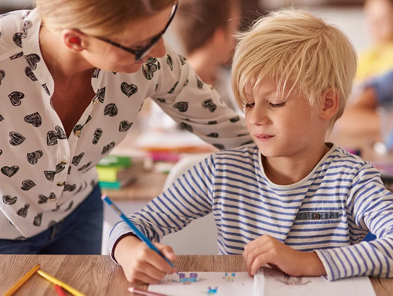 Lehrerin hilft einem Kind beim Lernen